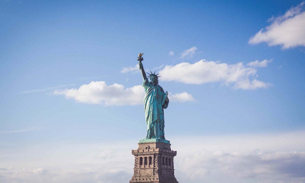 a statue of liberty with a blue sky and clouds