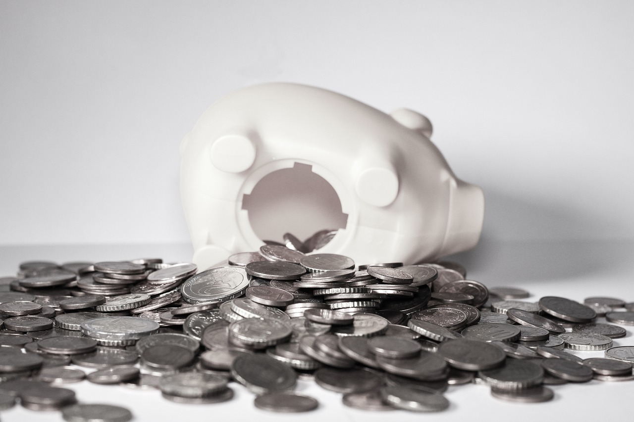 a white plastic piggy bank on a pile of coins