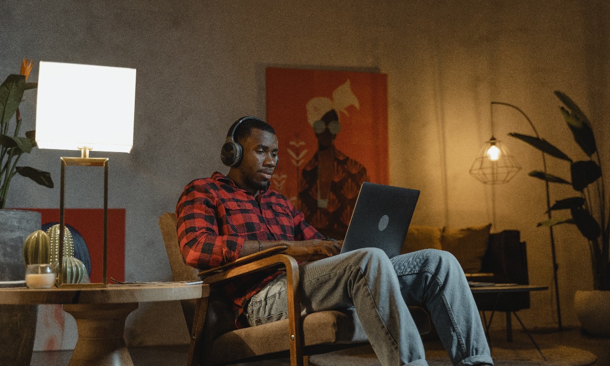a man sitting on a chair with a laptop and headphones on