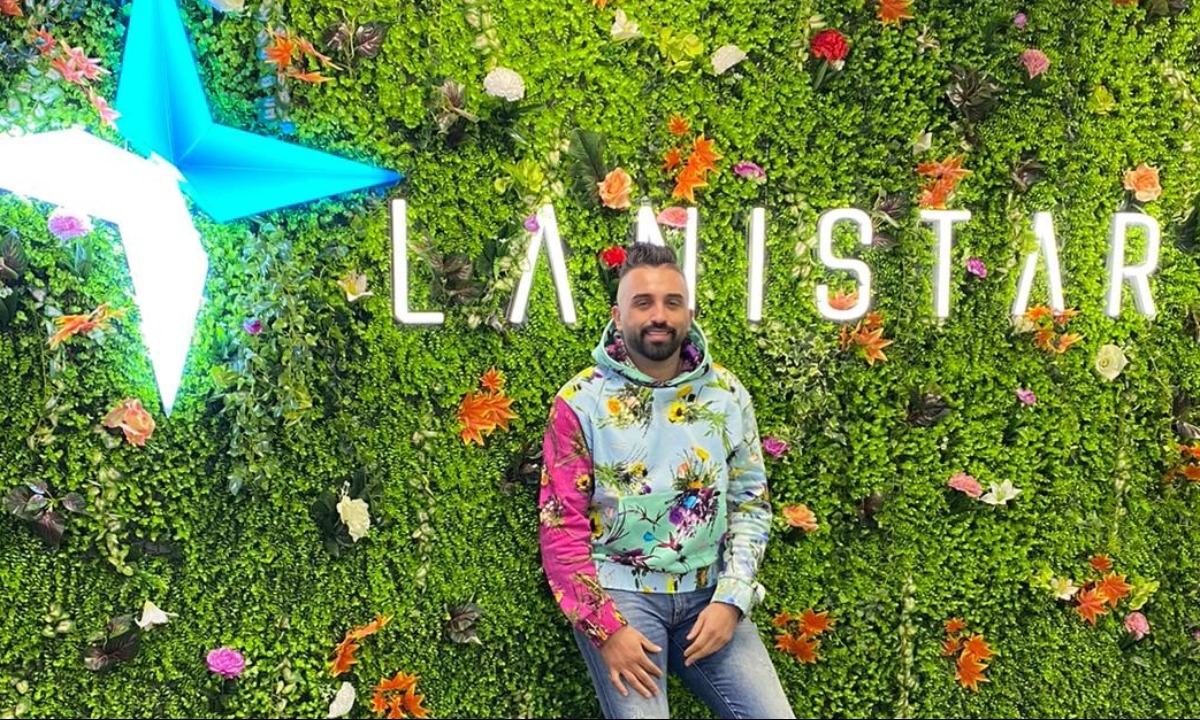 a person sitting in a field of flowers with a sign behind him