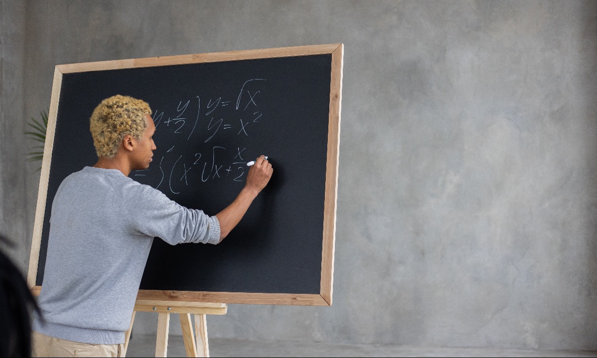 a man writing on a chalkboard