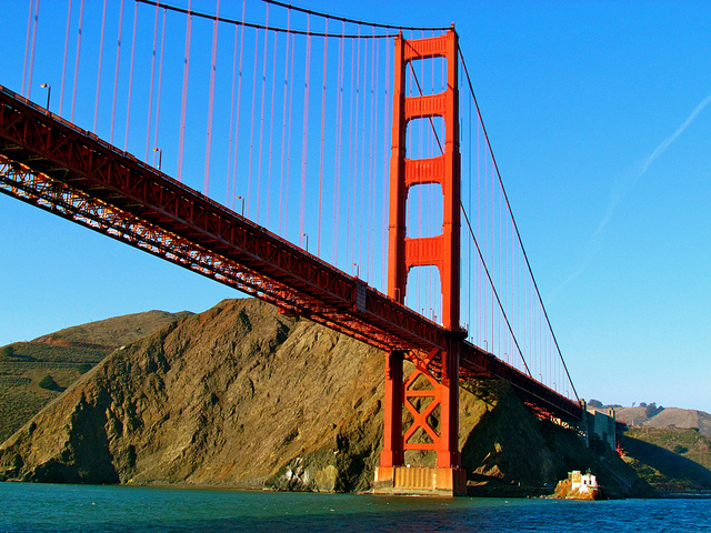 a red bridge over a body of water with Golden Gate Bridge in the background