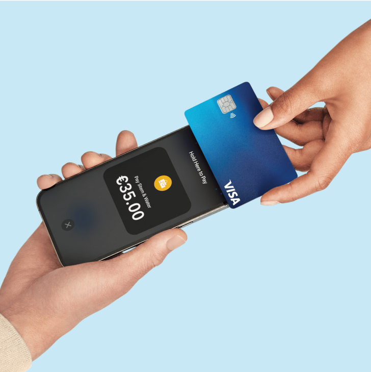 Close-up of two people, one holding a cell phone and the other holding a credit card to the cell phone to pay.