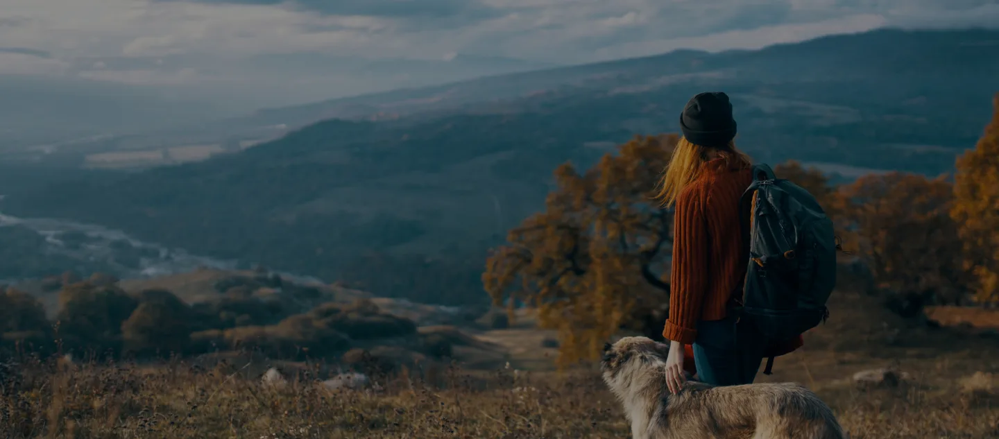 Women with her dog in the mountains looking off into the distance