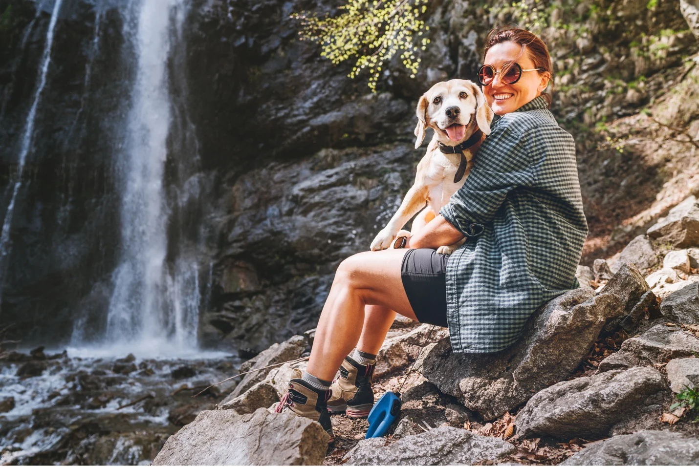 Woman hiking with a dog at a waterfall
