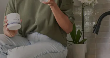 a person holding a bottle of creatine