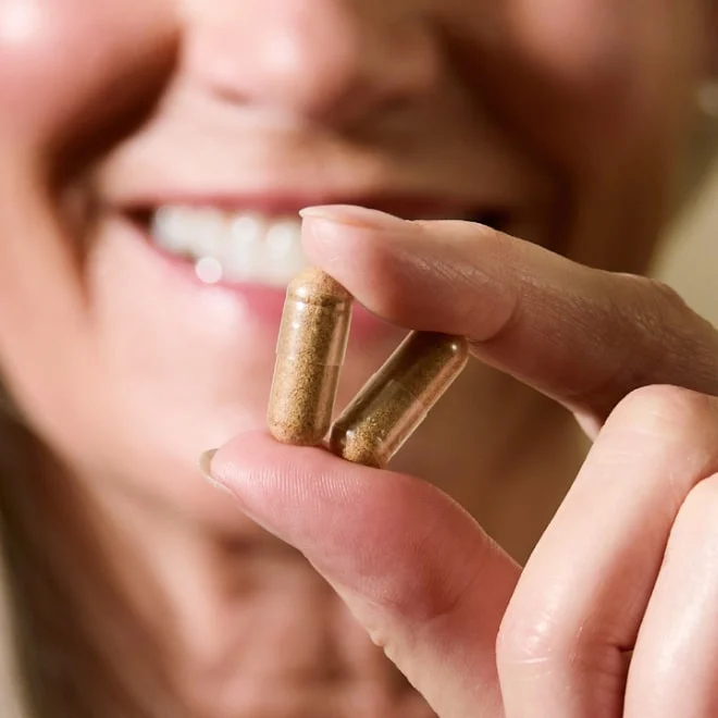 a woman holding 2 capsules