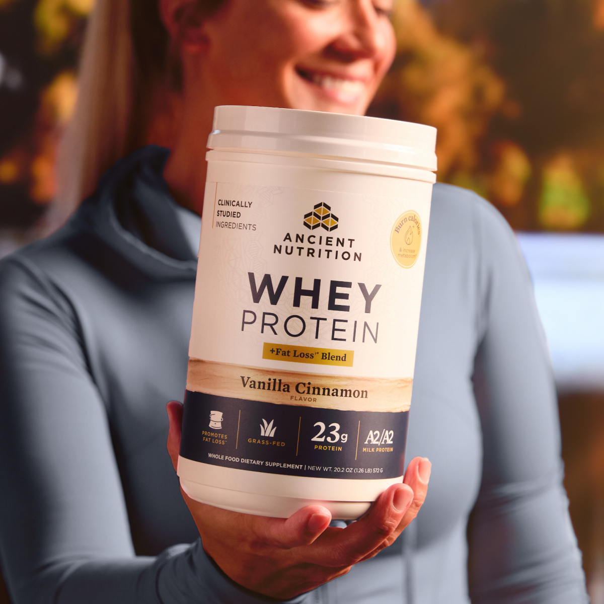 A woman holding a bottle of whey lean + Fat Loss