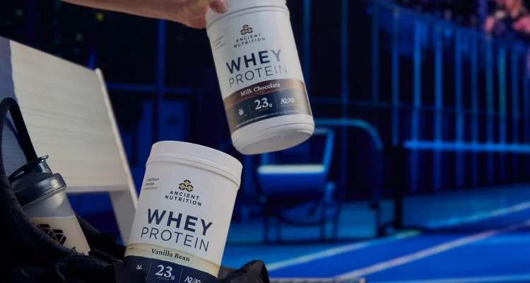 2 bottles of whey protein powder next to a tennis court