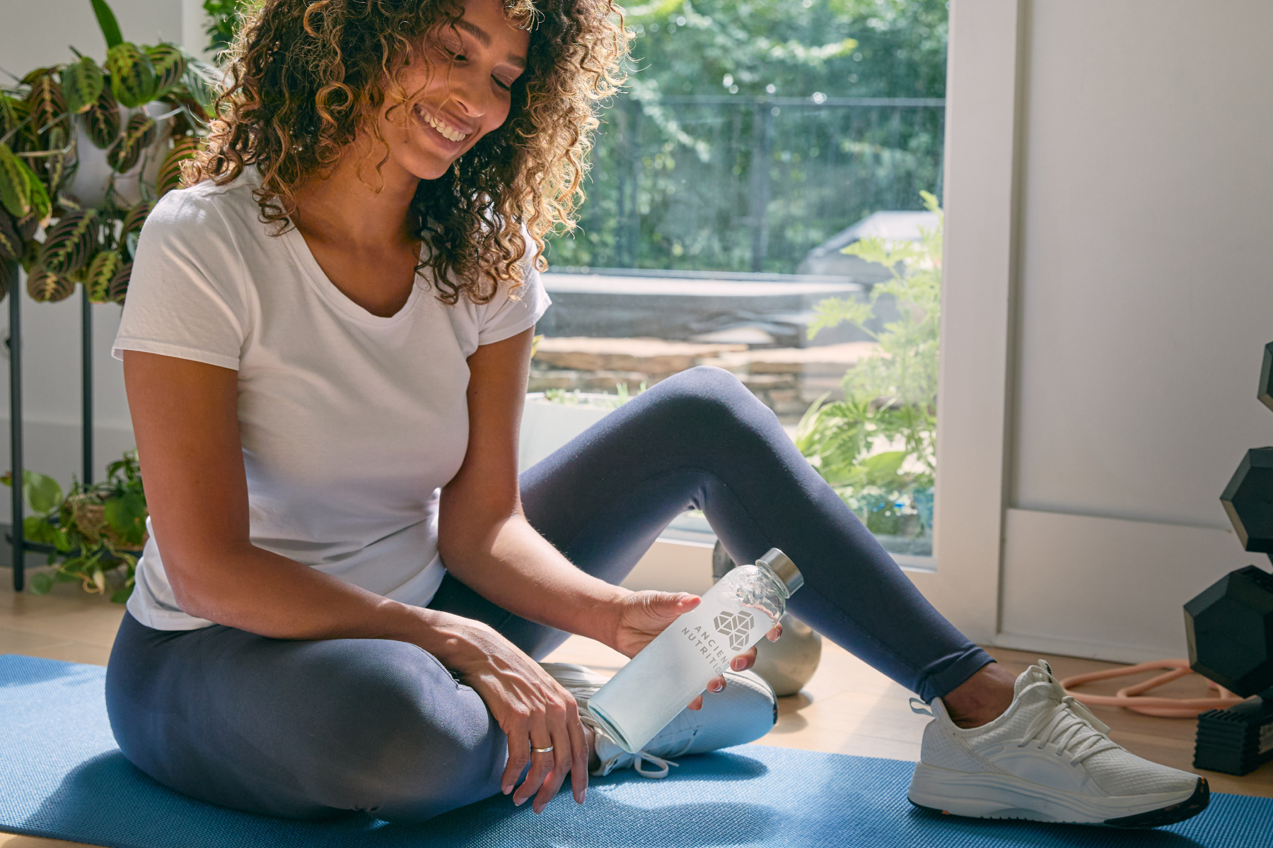 a person sitting on the floor with a ancient nutrition water bottle