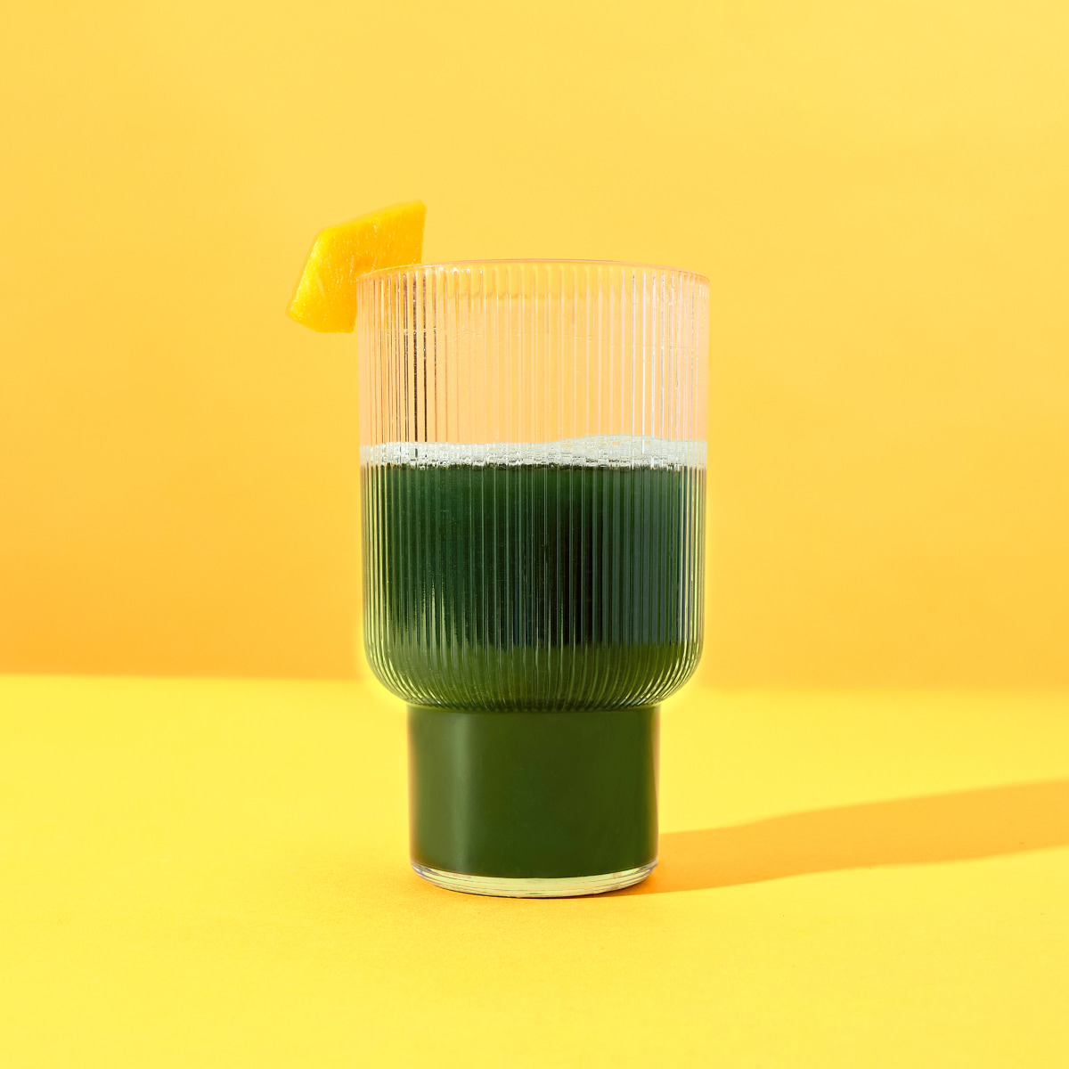 a glass of supergreens on a yellow background