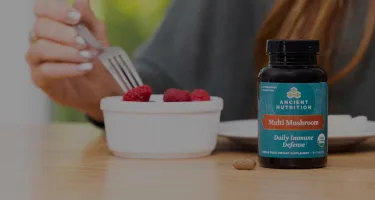 multi mushroom bottle next to a bowl of berries