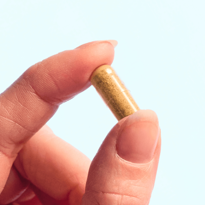 fingers holding a capsule