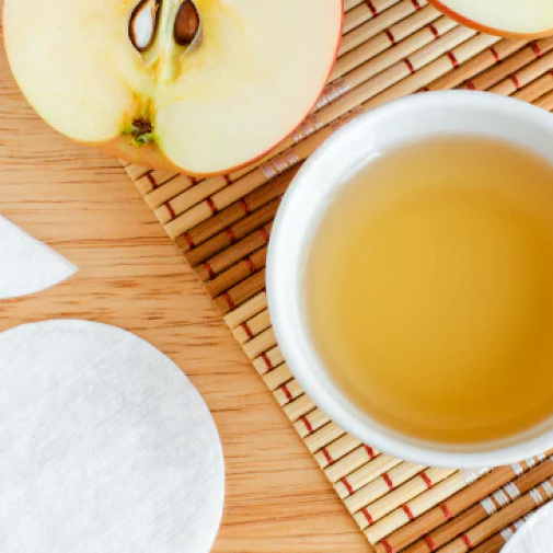 herbal cider vinegar in a cup next to makeup pads