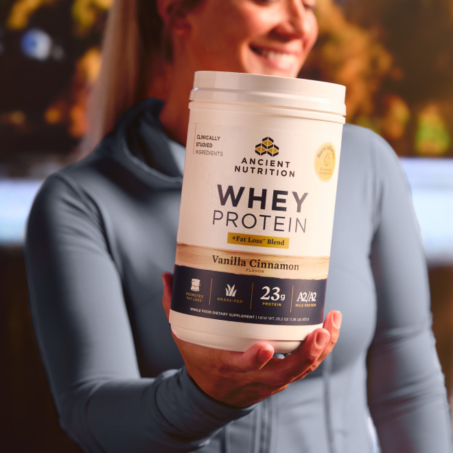 A woman holding a bottle of whey lean + Fat Loss