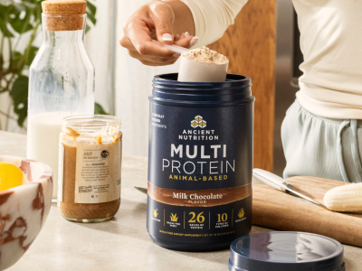 a person scooping a scoop out of a multi protein animal based chocolate bottle