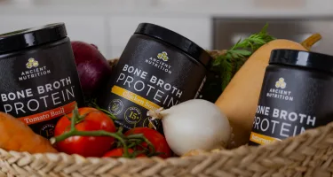 bone broth protein savory bottles behind vegetables