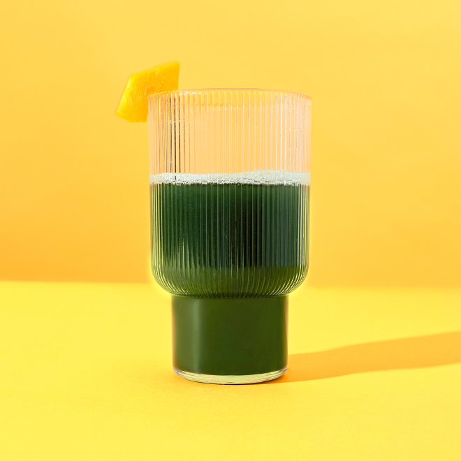 a glass of supergreens on a yellow background