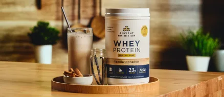 Bottle of whey protein + fat loss on a tan background