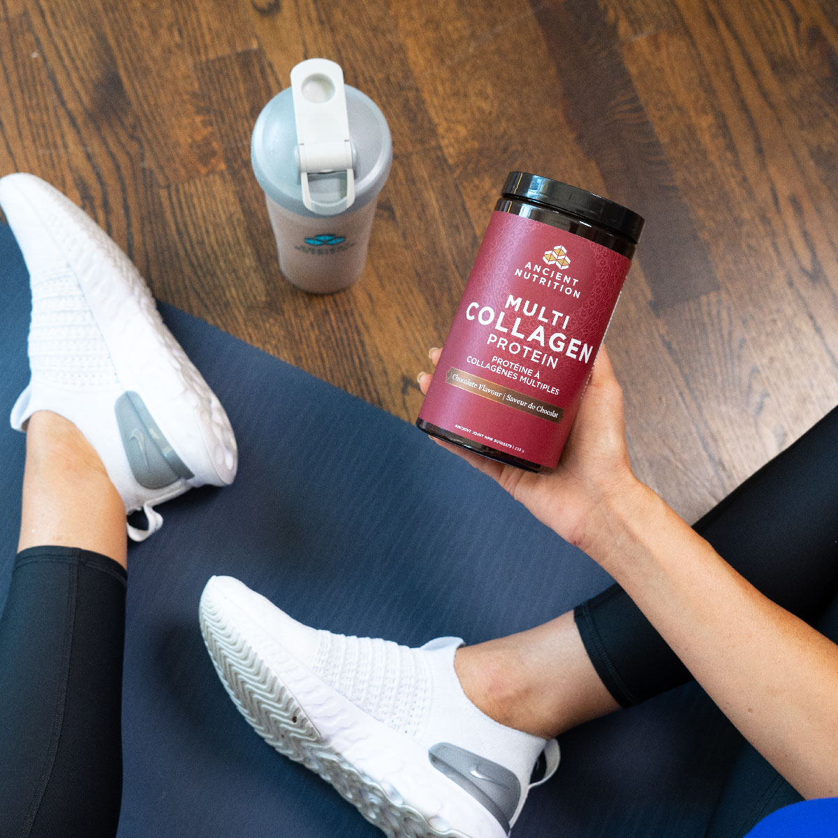 a person holding a bottle of multi collagen protein powder on a workout mat