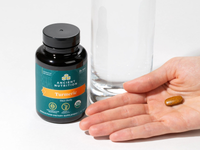 a persons hand next to a bottle of turmeric