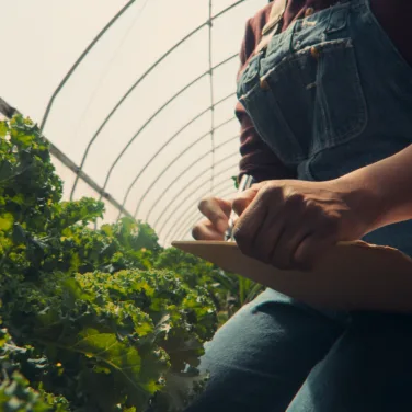 researcher in greenhouse with clipboard and pen