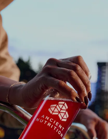 a person holding an ancient nutrition branded water bottle