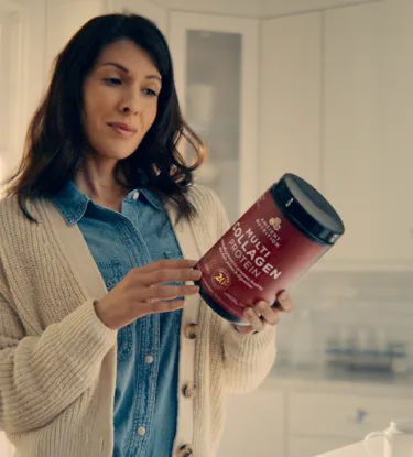woman looking at collagen bottle
