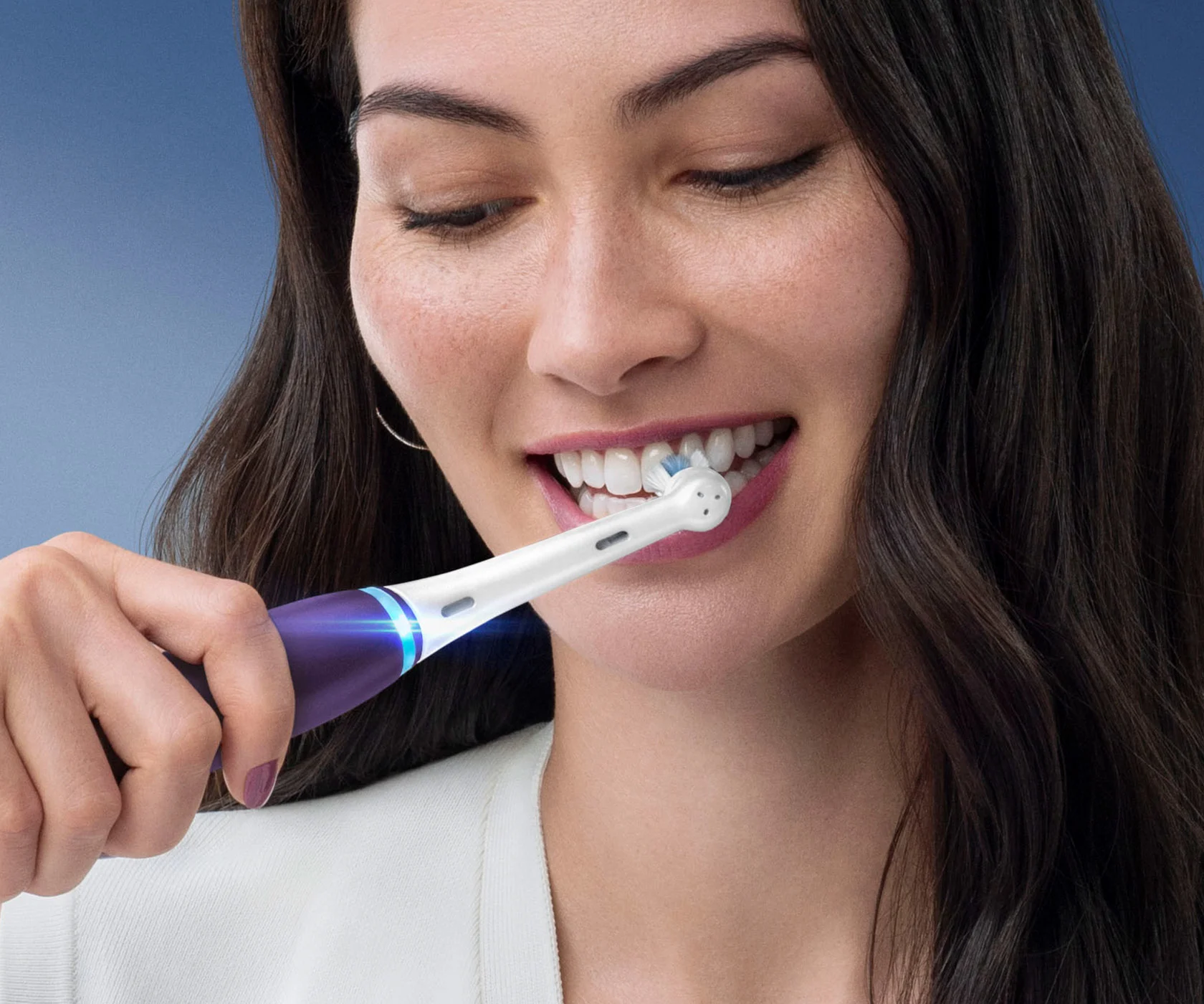 Woman brushing her teeth with Oral-B's iO Series 8 electric purple  toothbrush 