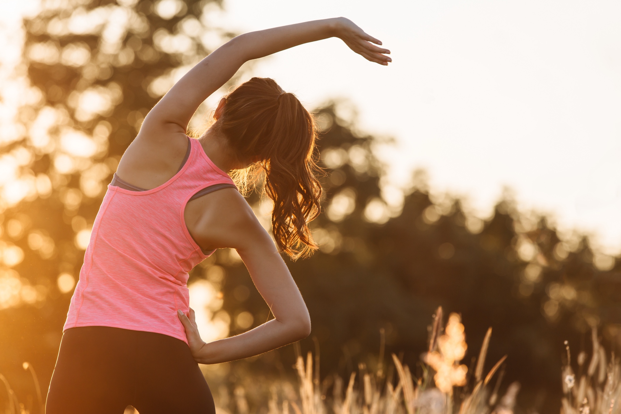 Young female workout before fitness training session at the park. Healthy young woman warming up outdoors. She is stretching her arms and looking away,hi key. - By GP PIXSTOCK - QF - 03