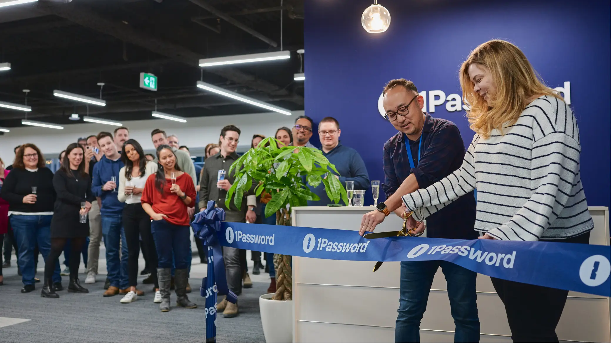 Zeremonie zur feierlichen Eröffnung im 1Password-Büro mit versammelten Leuten und einem blauen „1Password“-Band.