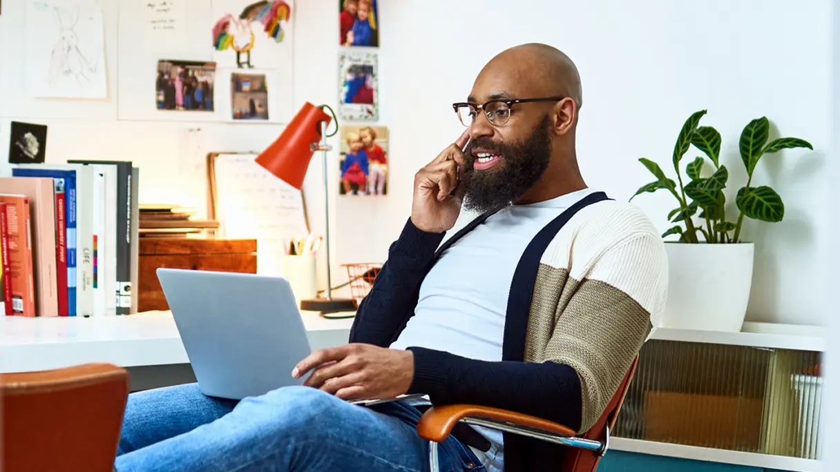 A man working on a laptop and talking on a cell phone while using 1Password's personal password manager