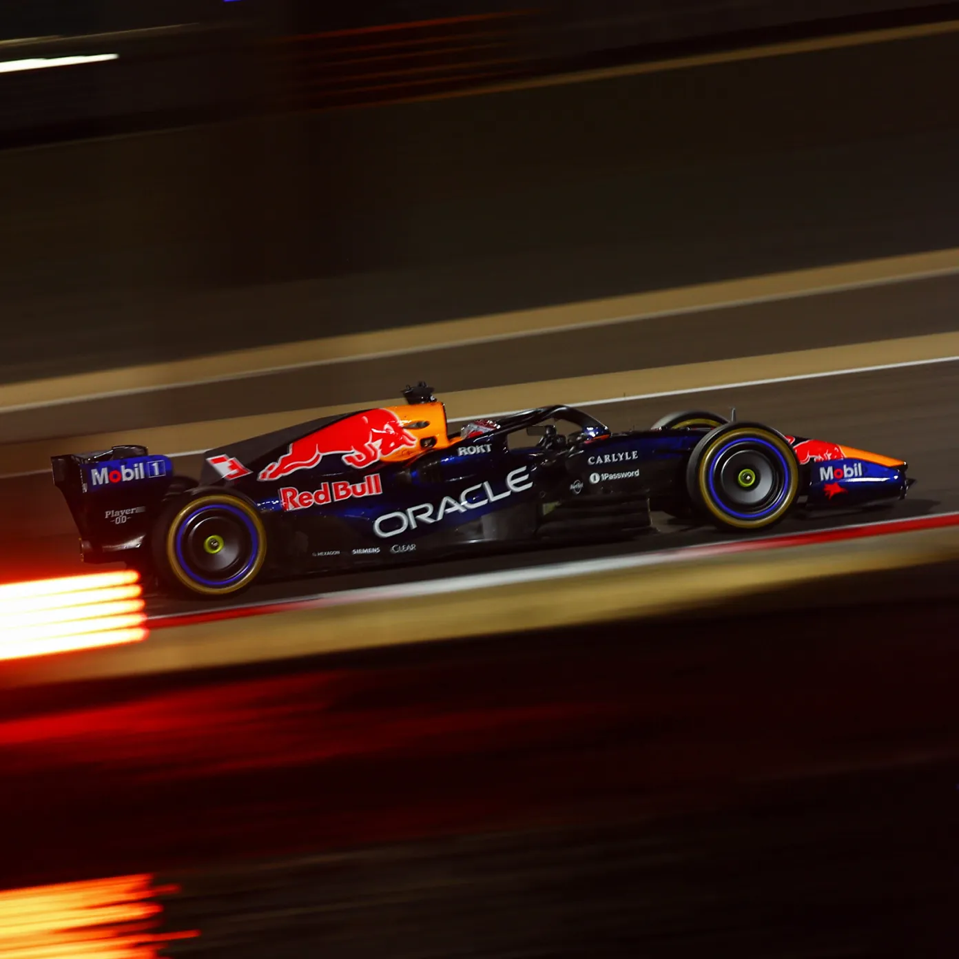 Oracle Red Bull Racing Formula 1 car speeding along the track at night, captured with motion blur and light streaks.