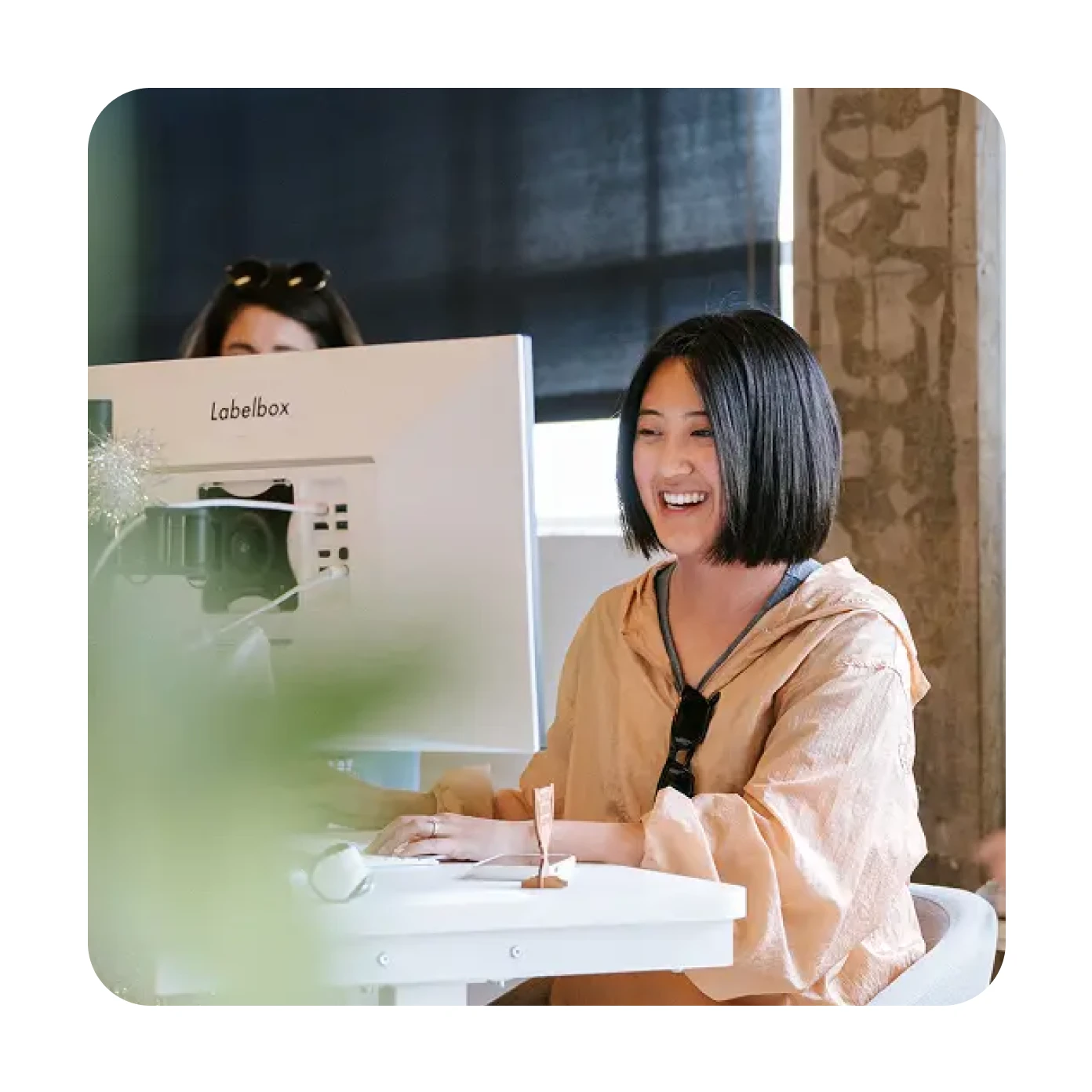 Two people working together at a desk with a computer and label maker in an office setting.