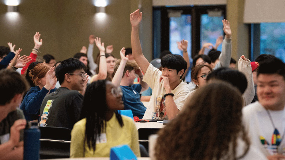 A group of international students attend class at Gonzaga University and raise their hands. 