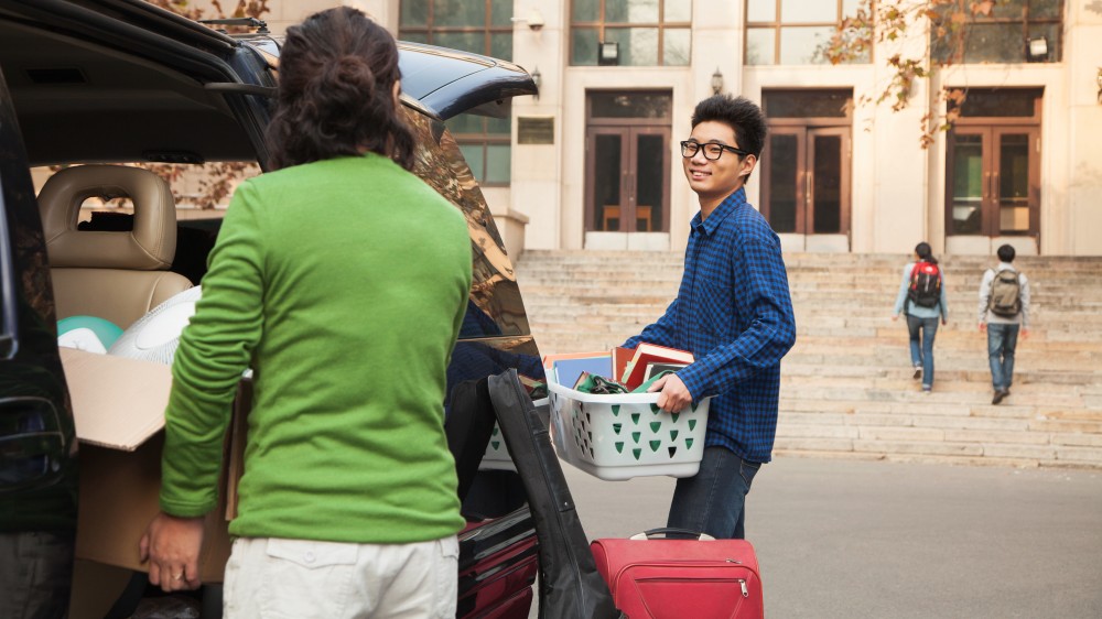 Two international students packing their vehicle in preparation for a move.