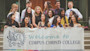 A group of international students stand on stairs on the UBC campus in Vancouver and hold up a banner saying Welcome to Corpus Christi College