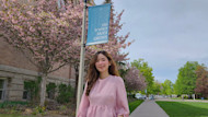 Gonzaga Global MBA student Daisy Le stands outside on campus in front of a flowering tree and green lawn and smiles for the camera