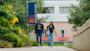Two international students at the University of Texas at San Antonio walk on a path in front of a brick building on campus