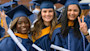 A group of female international students at Villanova University stand in their caps and gowns on graduation day and hold their new degrees. 
