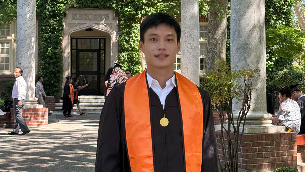 Ming-Hao, aka Howard, an international student at the University of the Pacific, stands on campus in his graduation gown after earning his graduate degree in computer science.