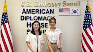 Somin, an international student from South Korea at the University of South Carolina, stands next to the US and South Korean flags at the U.S. Embassy in Seoul.