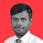 Shorelight author Deshan Mendis smiles for the camera against a red background 