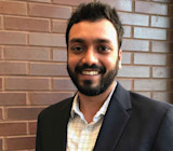 Shrikant, a grad student from India at Cleveland State University, smiles for the camera while standing in front of a brick wall