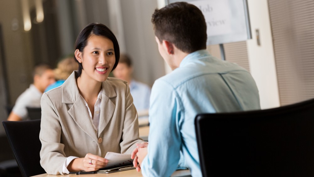 A female international student from Asia sits across from a male career counselor and discusses finding jobs in the USA
