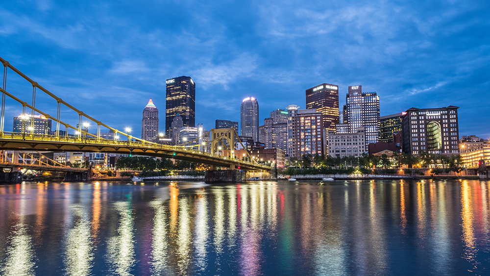 The Pittsburgh skyline is seen over the region's three rivers at night