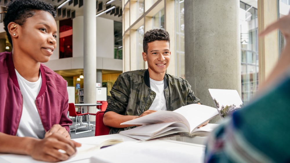 A male international student sits at a table in front of an open textbook