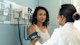 A woman has her blood pressure checked by a health worker wearing a white coat.