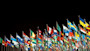 A row of international flags fly against a black background