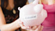 Two female international students hold out a piggy bank with the word COLLEGE taped on it